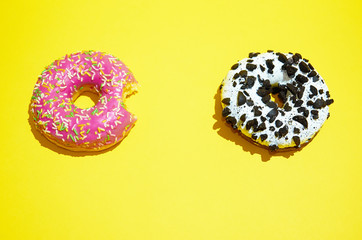 Pink and white donuts lie on a yellow background.