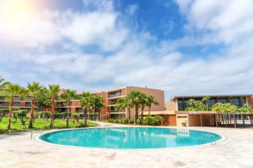 Fototapeta na wymiar Modern luxurious pool with clean, clear, blue water, palm trees
