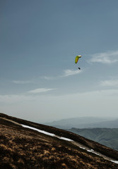 Skydiver flies beside the peak of mountains