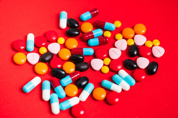 A lot of pill on the red background. Medicine pills, tablets and capsules.