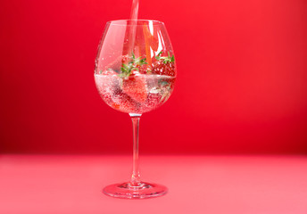Bright juicy selected strawberries in a large glass with soda.