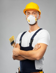 repair, construction and building - male worker or builder in helmet and respirator mask with paint...