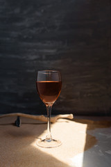 Glass of red wine in arched sunlight on the sand.