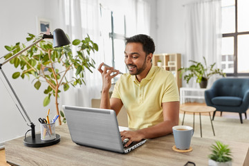 technology, remote job and lifestyle concept - happy indian man with laptop computer working and...
