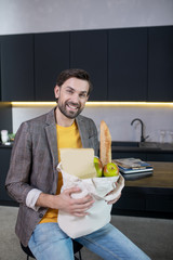 Young bearded man holding a bag with food and smiling