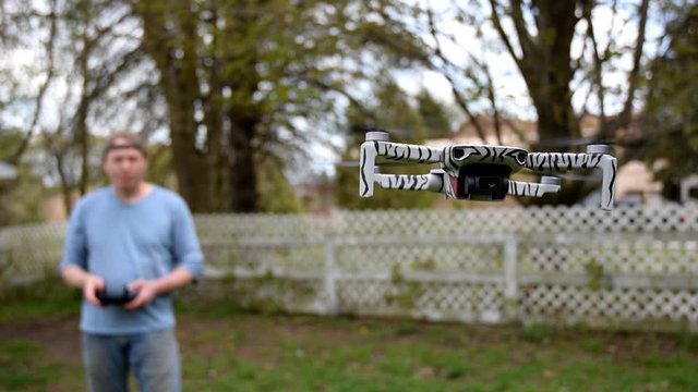 A Man Holding Controller Flying A Drone In The Garden - Close up shot