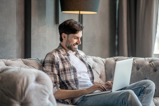 Young adult man with laptop on the couch.