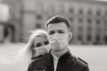 Obraz premium Young couple in love in protective medical mask on face outdoor at street. Environmental pollution concept. Guy and girl in virus protection