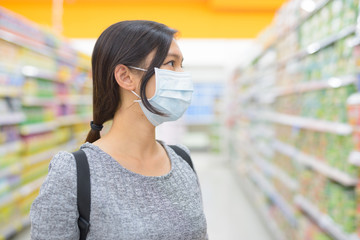 Profile view of young Asian woman wearing mask and shopping with distance at the supermarket