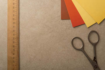 Wooden vintage ruler, colorful paper and aged scissors on stone surface. Diy, hobby, handmade, artist and homemade decoration concept photo.
