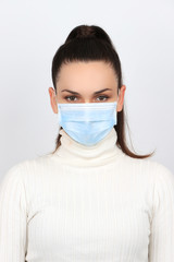 Jeune femme brune portant un masque chirurgical pour se protéger des virus isolée sur fond blanc