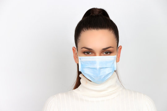 Jeune femme brune portant un masque chirurgical pour se protéger des virus isolée sur fond blanc