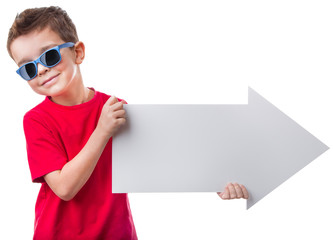Cheerful little boy in sunglasses holding a big empty white arrow and looking at camera, isolated on white background