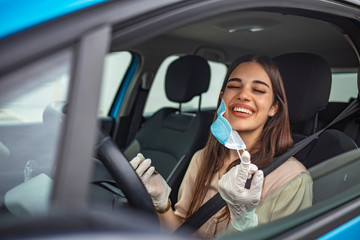 Woman removing her protective mask once in the car. Woman during pandemic isolation at city. Removing mask from face. Woman removes medical mask. Protection against viruses, germs, pneumonia epidemic