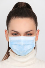 Jeune femme brune portant un masque chirurgical pour se protéger des virus isolée sur fond blanc