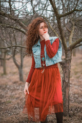 Autumn fashionable ideas. Woman in jeans vest and marsala knitted-lace dress . Modern fashion