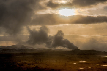 Fototapeta na wymiar Crowd of smoking chimneys and puddles of boiling water in Hverir, Iceland.