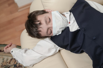 Obraz premium coronavirus covid-19 epidemic outbreak quarantine concept of small boy in medical mask and school uniform lying at home being sick with high temperature