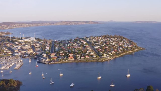 Aerial high angle footage moving over Rosny Hill Lookout, Bellerive, Kangaroo Bluff Reserve and Bellerive Beach on the banks of the Derwent River east of Hobart, Tasmania, Australia at sunset