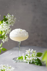 Sparkling wine Ice Cream Floats cocktail in a wine glass and blossom branches on gray background....