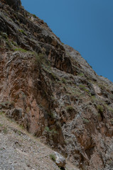 mountains of Central Asia. a narrow road between mountains. rapid river and sparse vegetation. there are no people.
