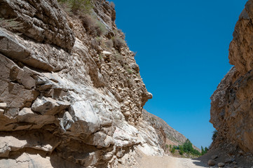 mountains of Central Asia. a narrow road between mountains. rapid river and sparse vegetation. there are no people.