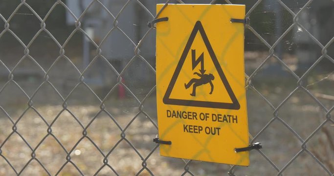 Yellow Danger of Death sign on a chainlink fence