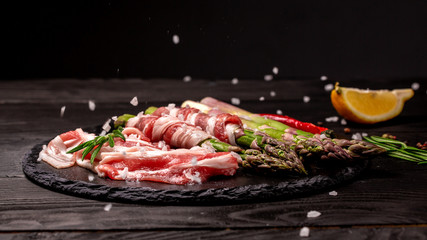 Plate with bacon wrapped asparagus on dark background. Food recipe background. Close up