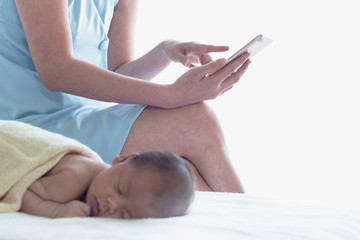 Asian mum spends time while the baby sleeping contact the business or search for information with a smartphone, selective focus