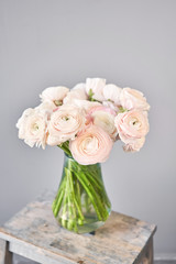 Spring background, flower Wallpaper. Persian buttercup. Bunch pink ranunculus flowers on light gray background. Vase on vintage wooden table. Wallpaper