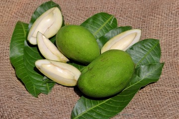 Green Mango with Mango Leaves on Burlap Background with Selective Focus