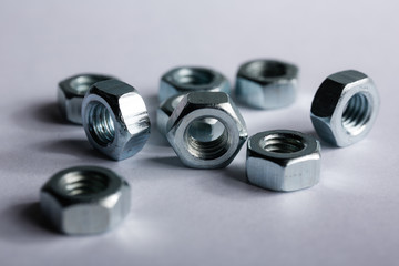 Metal nuts neatly laid out on a white background. Macro shooting. Construction and repair concept