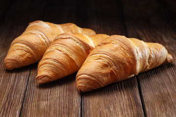 set of fresh baked croissants on wooden table
