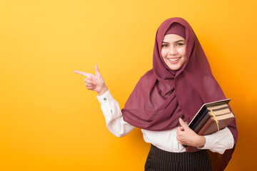 Beautiful University student with hijab portrait on yellow background