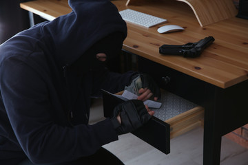 Dangerous masked criminal stealing money from house