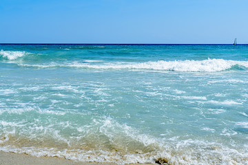 Big wave of ocean on sandy beach with blue clean sky
