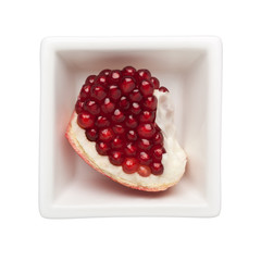 Piece of pomegranate in a square bowl isolated on white background; 

