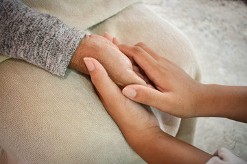 Close up granddaughter takes care of the health sick grandmother at home by holding hands. Lifestyle support the love of the family.
