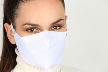 Jeune femme brune portant un masque grand public blanc pour se protéger des virus isolée sur fond blanc