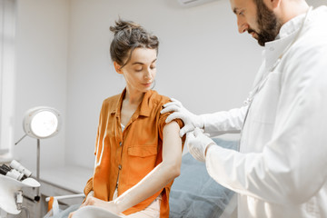 Obraz premium Healthcare worker gives an injection of a vaccine or some medication to a young girl in the office. Vaccination concept