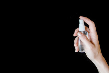 Girl hand holds hand sanitizer with black background, prevention covid-19