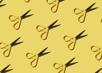 Seamless colorful pattern: stationery scissors on yellow background flat lay. Close-up, hard light.