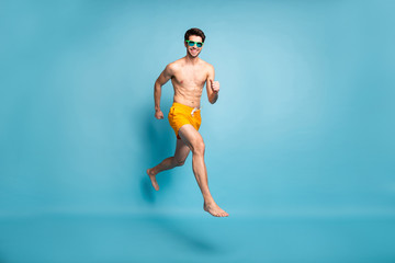 Full length body size view of his he nice attractive cheerful cheery guy in swimming shorts jumping...