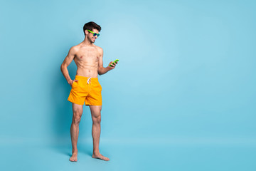 Full length body size photo of cheerful toothy handsome beaming man holding telephone browsing in...
