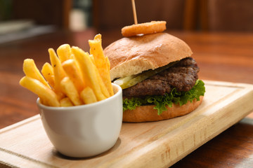 Homemade hamburger with beef, tomato, lettuce and sweet and sour sauce. French fries, onion rings. Serve on a wooden kitchen board. background image, copy space