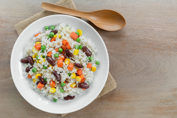 top view of fried rice with vegetable in a ceramic dish on wooden table. homemade style food concept.