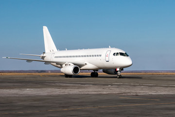 Fototapeta na wymiar White passenger airplane taxiing at the airport apron