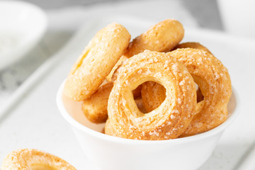 Puff pastry sprinkle with sugar in a white plate on a light gray background. Cookies sprinkle with sugar close-up. Sweet pastries