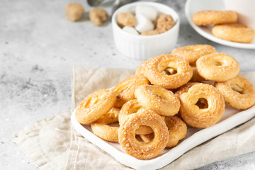 Puff pastry sprinkled with sugar in a white plate on a light gray background. Cookies sprinkled with sugar. Sweet pastries