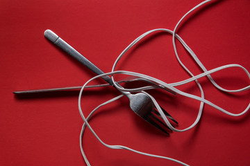 Iron forks on a red background with a wire instead of noodles